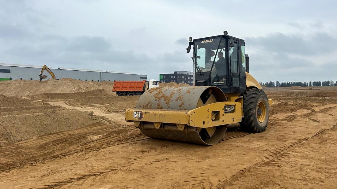 Аренда виброкатка грунтового Caterpillar для уплотнения песка под строительство складских помещений в Хатежино